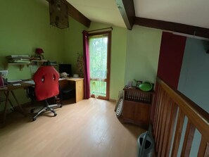 Ein Zimmer mit Schreibtisch, Stuhl, Fenster und einem kleinen Schrank.