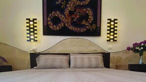 Un dormitorio con una cama, dos lámparas fijadas a la pared y un adorno grande sobre la cama.