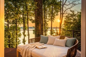 A balcony with a wicker sofa, a book, and a blanket.