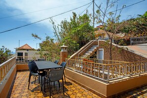 A terrace with a table and chairs, a staircase, and a view of a building in the background.