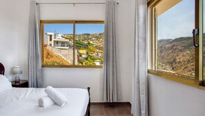 Ein Hotelzimmer mit großem Fenster, einem Bett, einem Nachttisch und einer Lampe.