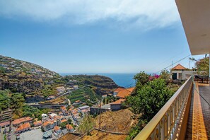 A coastal town with terraced houses, a sea view, and a balcony overlooking the landscape.