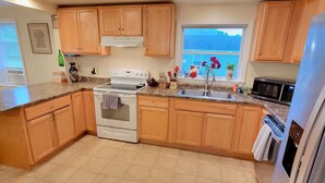 A kitchen with wooden cabinets, a white stove, a sink, and a refrigerator.
