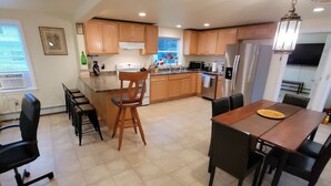 A spacious kitchen with wooden cabinets, a dining area with a table and chairs, and a large island with a sink.