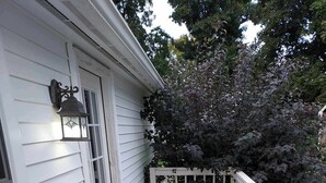 A wooden deck with a white railing, a door, and a window.