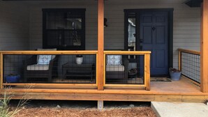 A wooden porch with a railing, a window, and a door.