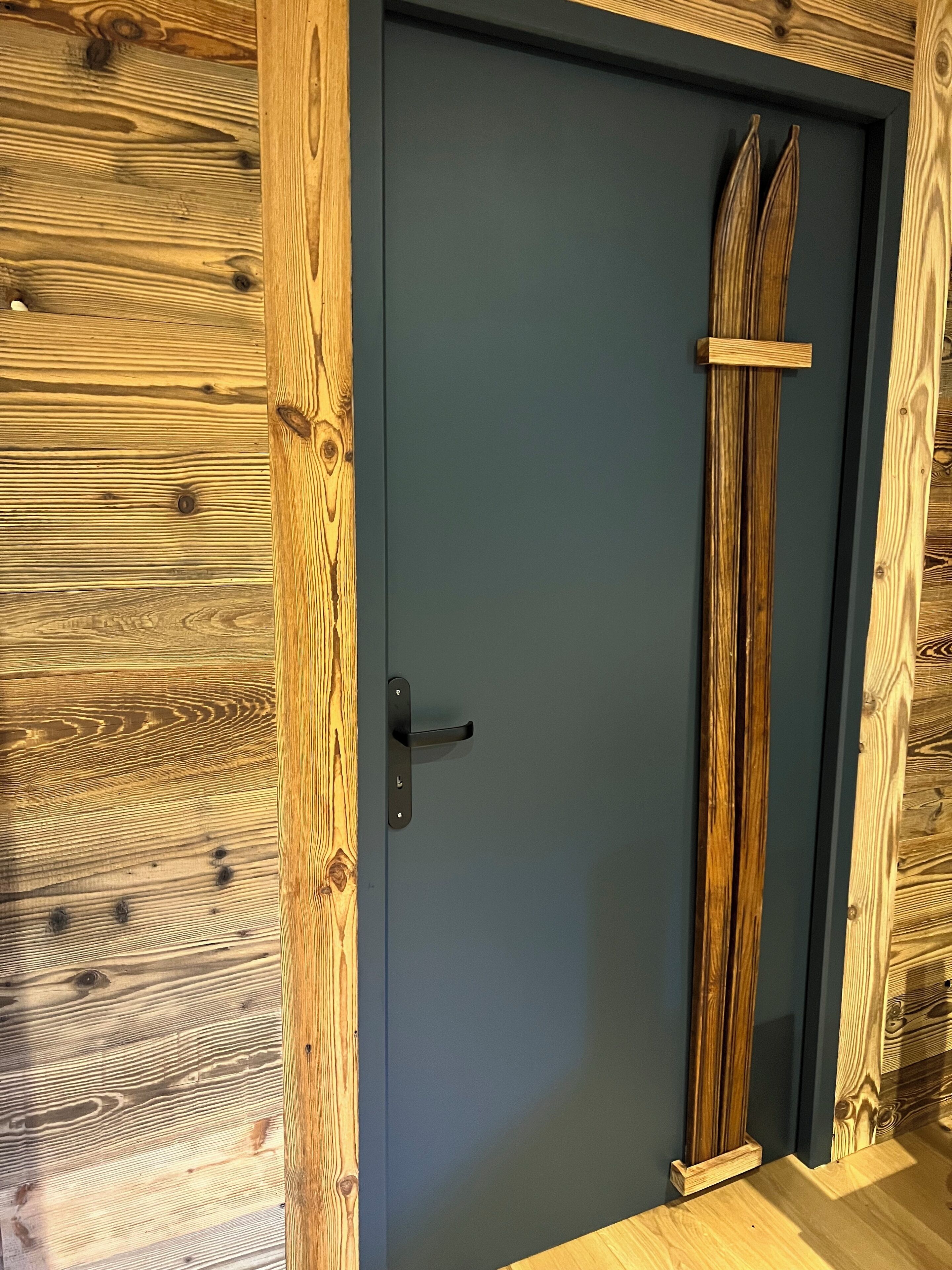 Una puerta de madera con un marco gris oscuro y un detalle vertical de madera.