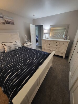 A bedroom with a bed, dresser, and a mirror above it.