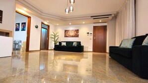 A spacious lobby with a polished granite floor, a dark-colored sofa, a reception desk, and a large painting on the wall.