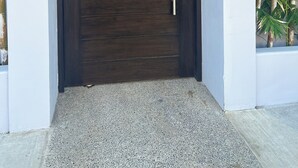 Une entrée moderne avec une porte en bois foncé, une poignée en métal et une petite plaque au-dessus de la porte.