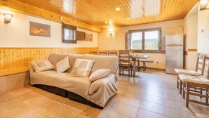 Una habitación acogedora con sofá, mesa de comedor, sillas y un refrigerador.