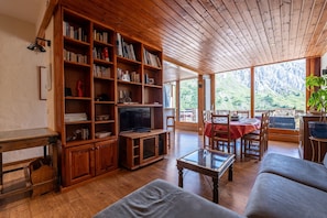A wooden interior with a bookshelf, TV, dining table, and chairs. - Apartment 'Shamrock 2B' with Mountain View, Balcony and Wi-Fi (Tignes)
