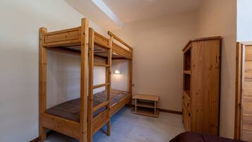 Una habitación con una cama litera, un armario de madera y un pequeño banco.