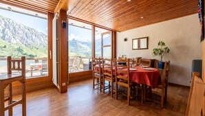 A dining area with wooden chairs and tables, a view of mountains, and a wooden ceiling. - Apartment 'Shamrock 2B' with Mountain View, Balcony and Wi-Fi (Tignes)