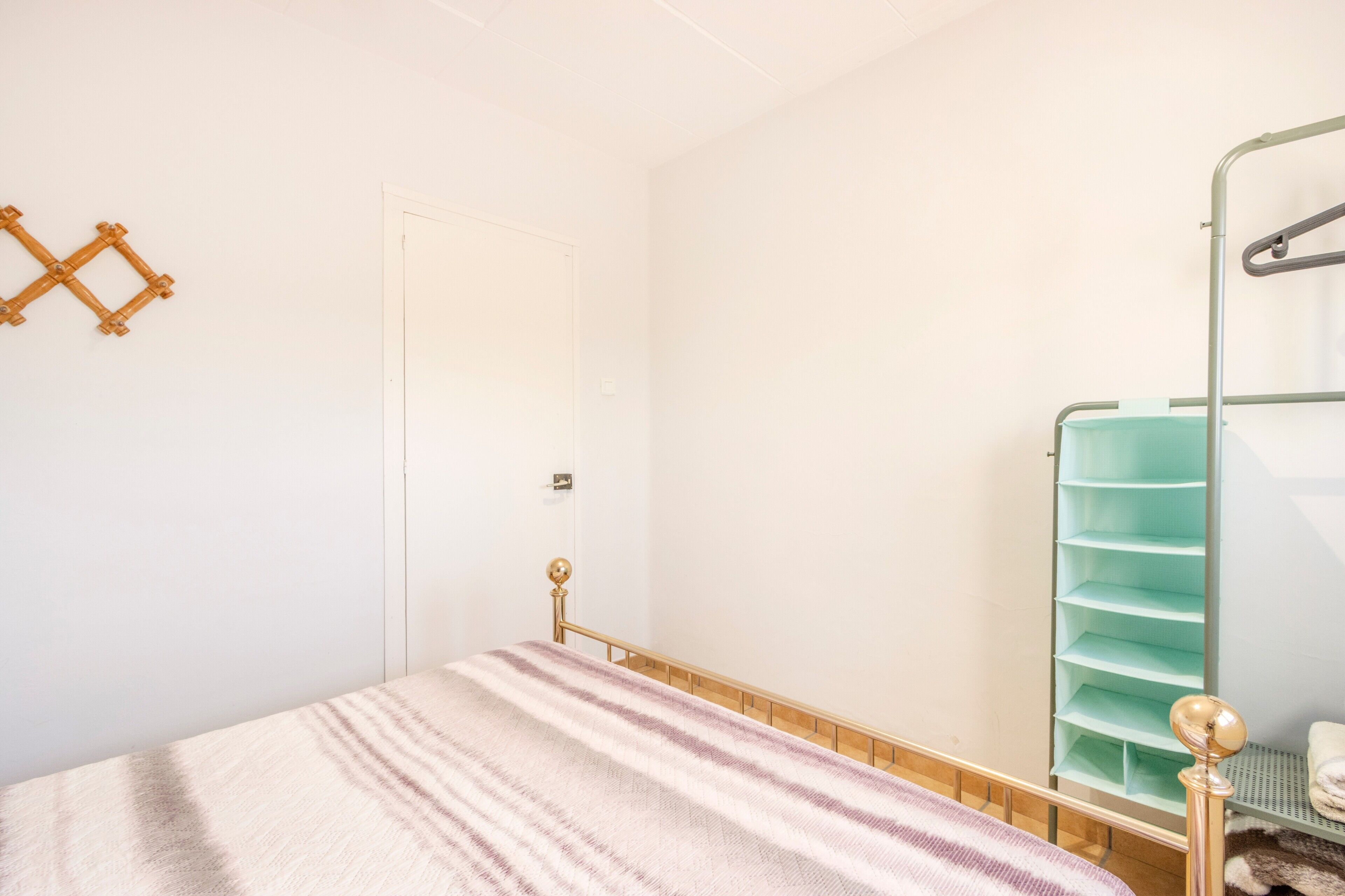 Un dormitorio con cama, armario y puerta.