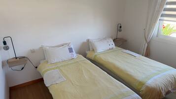 Ein Zimmer mit zwei Einzelbetten, jeweils mit Nachttisch und Lampe.