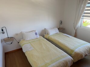 Une chambre avec deux lits simples, chacun étant équipé d’une table de chevet et d’une lampe.