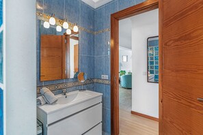 Un baño con tocador de madera, espejo y lavabo.