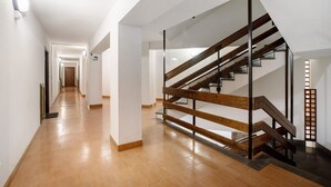 Un intérieur moderne avec un escalier en bois, un long couloir et un luminaire au plafond qui diffuse une lumière vive.