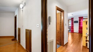 Un couloir avec des portes en bois, un radiateur et un téléviseur fixé au mur.