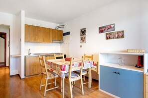 Una cocina con armarios de madera, una mesa de comedor con sillas y un mueble azul.