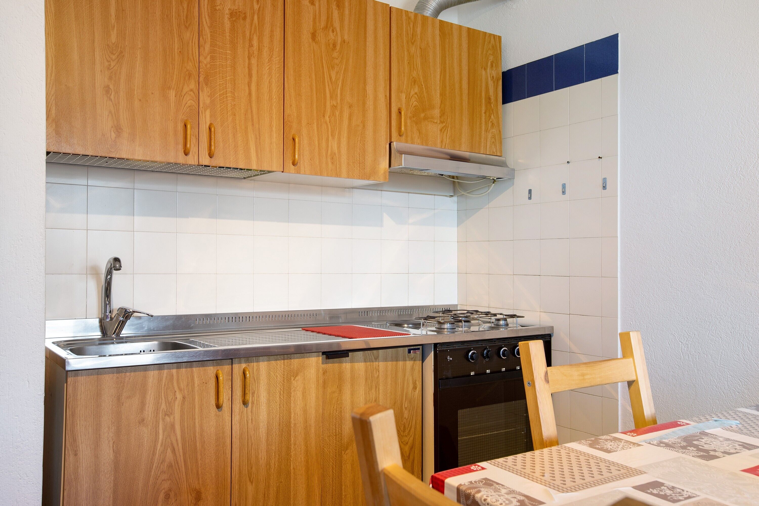 A kitchen with wooden cabinets, a stainless steel sink, a gas stove, and a built-in oven.
