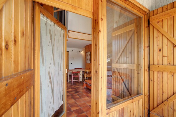 Un interior de madera con piso de baldosas, un escritorio y una cama.