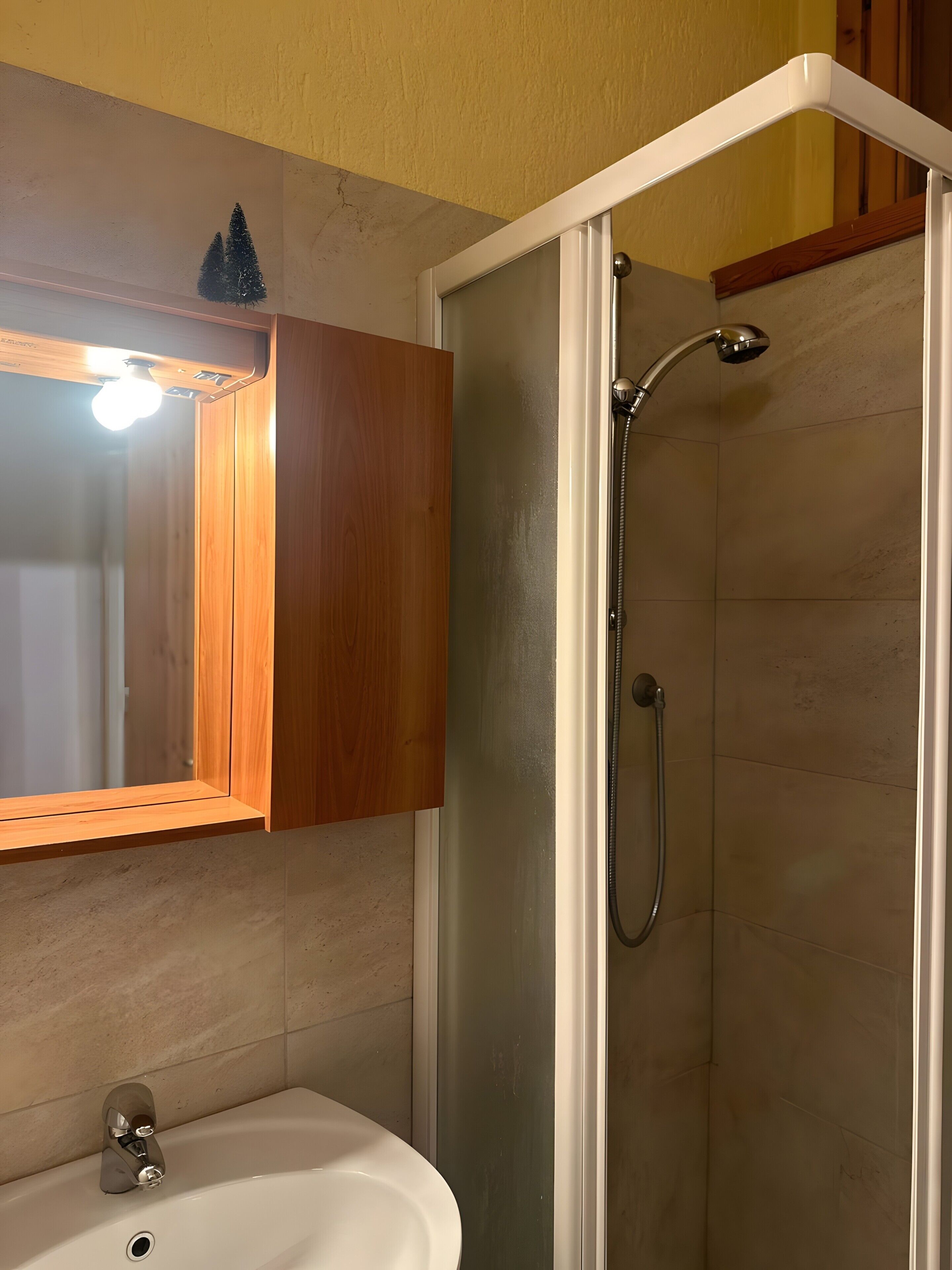 A bathroom with a wooden vanity, a sink, and a glass-enclosed shower.