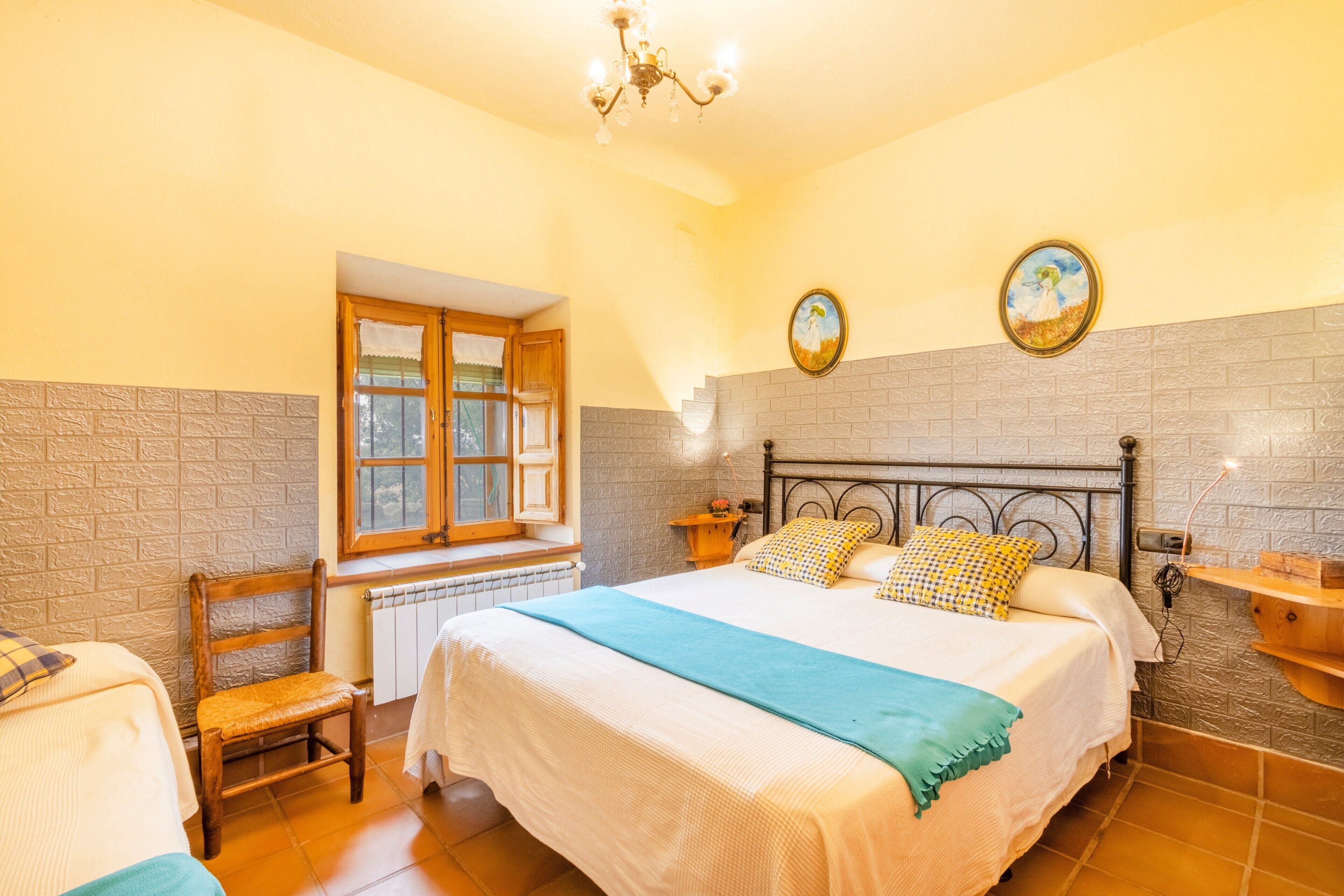 A bedroom with a bed, a window, a chair, and a wall-mounted shelf.