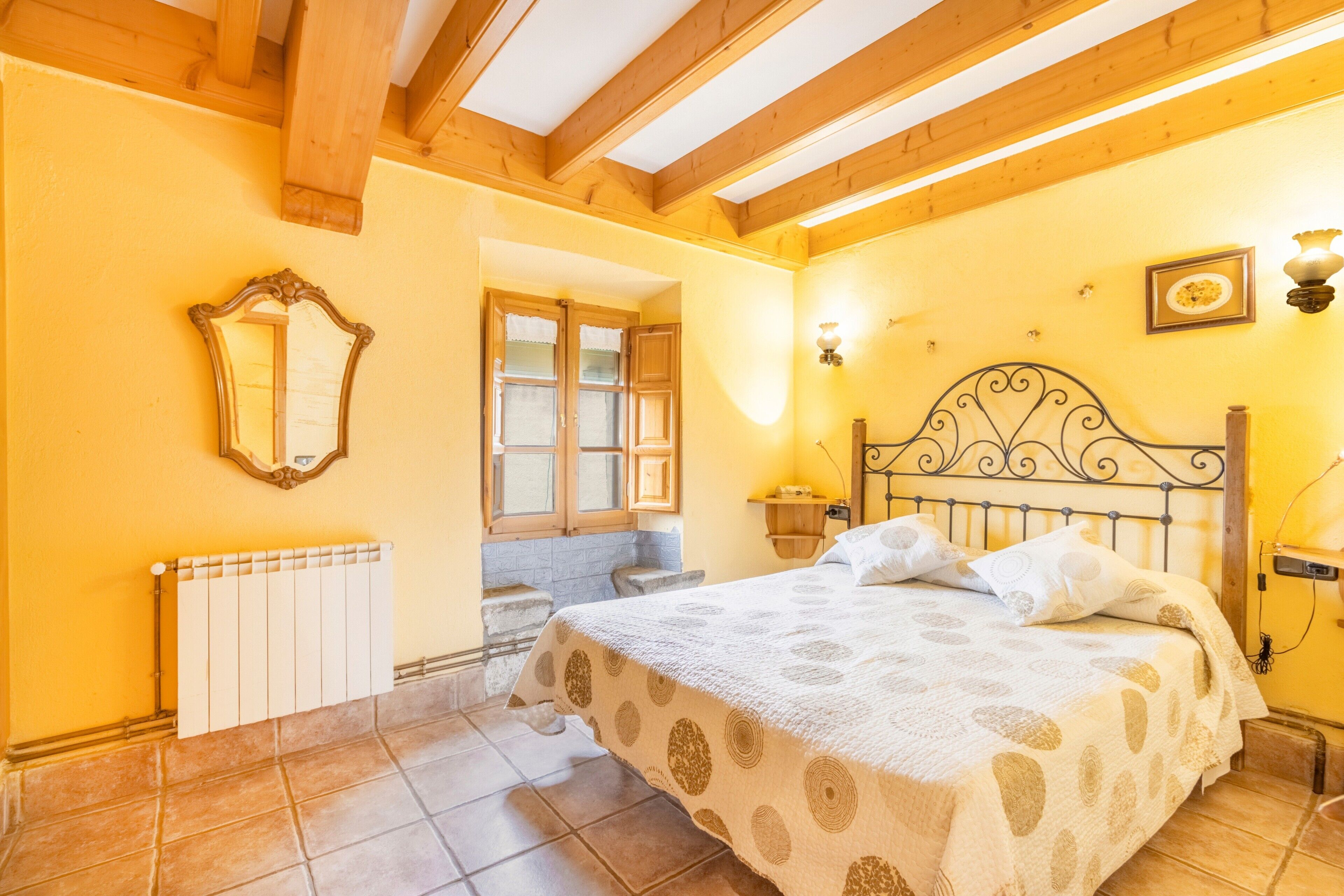 Un dormitorio con cama, radiador, ventana y un accesorio de luz instalado en la pared.