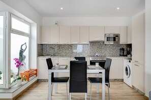 Cozinha moderna com área de refeições, backsplash de bancada de granito, eletrodomésticos de aço inoxidável e uma janela com vista.