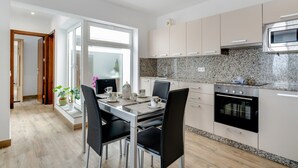 Cocina moderna con comedor, que incluye un amplio ventanal, encimeras de granito, electrodomésticos de acero inoxidable y horno empotrado.