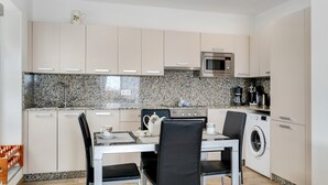 Una cocina moderna con comedor, salpicadero de granito, electrodomésticos de acero inoxidable y lavadora secadora integradas.