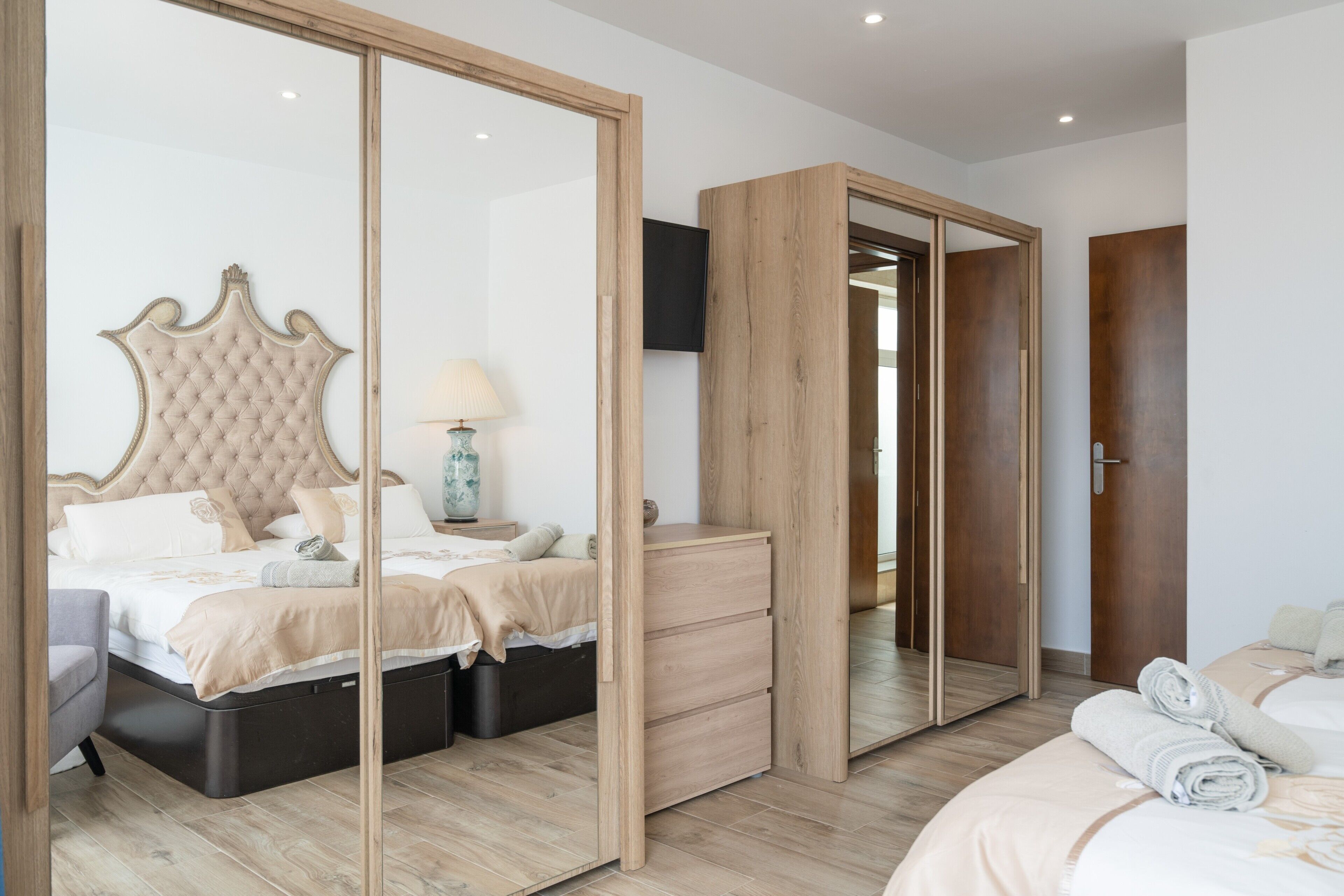 Une chambre à coucher avec un grand lit, une commode, un miroir et une armoire.