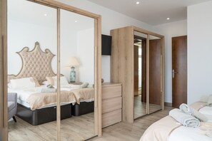 A bedroom with a large bed, a dresser, a mirror, and a wardrobe. - Vacation Home 'Garten Apartment' with Sea View, Private Terrace and Wi-Fi (Tías)