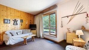 Une pièce confortable avec un canapé, une petite table, une lampe, une commode et une fenêtre avec des rideaux.