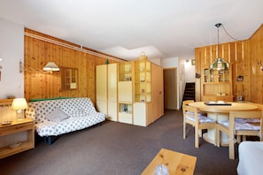 Una habitación acogedora con un sofá estampado de lunares, un aparador de madera, una mesa de comedor con sillas y una lámpara.