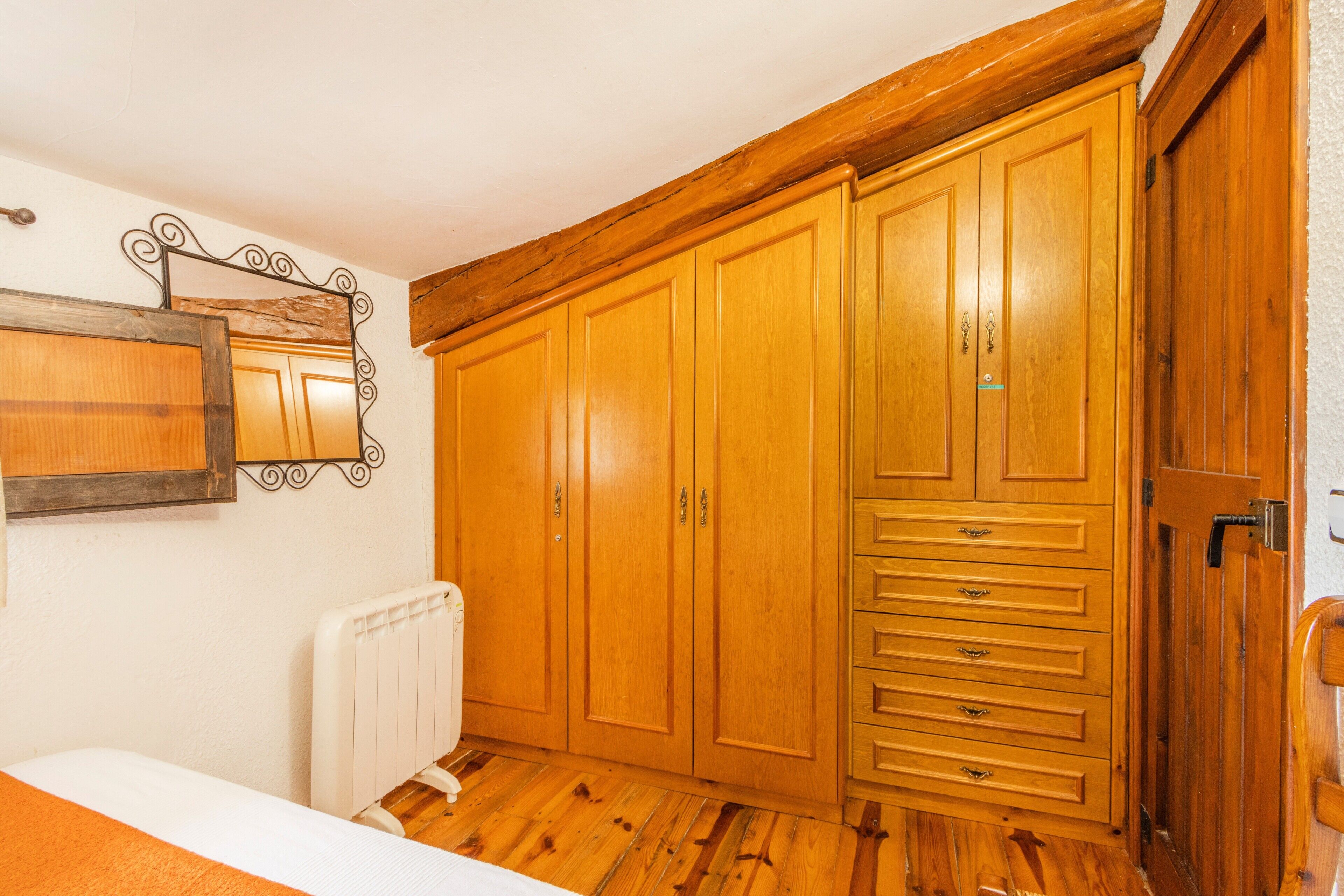 A room with wooden cabinets, a radiator, and a mirror on the wall.