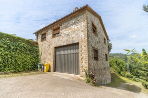A stone building with a large garage door, surrounded by greenery.