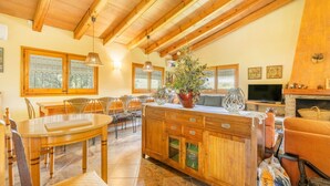 A wooden dining area with a table and chairs, a wooden cabinet with drawers, and a television on a stand. - Holiday Home 'La Granja' with Mountain View, Wi-Fi and Air Conditioning (Olvan)
