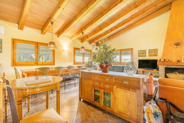 A wooden dining area with a table and chairs, a wooden cabinet with drawers, and a television on a stand.