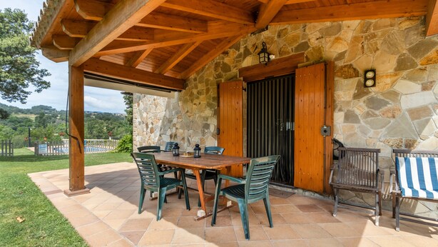 An outdoor patio with a stone wall, wooden pergola, and a table with chairs. - Holiday Home 'La Granja' with Mountain View, Wi-Fi and Air Conditioning (Olvan)
