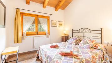 A bedroom with a bed, a window with curtains, a bedside table, and a nightstand.
