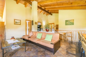 A cozy living room with a sofa, coffee table, and a dining area with chairs and a table.