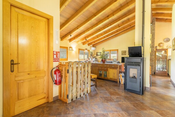 Una puerta de madera, un extintor, una cerca de madera, una zona de cocina con estufa y un suelo de baldosas.