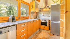A kitchen with wooden cabinets, a stainless steel dishwasher, a built-in oven, and a refrigerator. - Holiday Home 'La Granja' with Mountain View, Wi-Fi and Air Conditioning (Olvan)