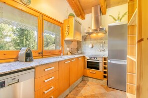 A kitchen with wooden cabinets, a stainless steel dishwasher, a built-in oven, and a refrigerator.
