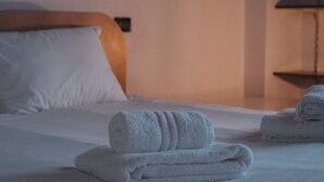 Un lit bien fait, avec du linge de lit blanc et des serviettes pliées.