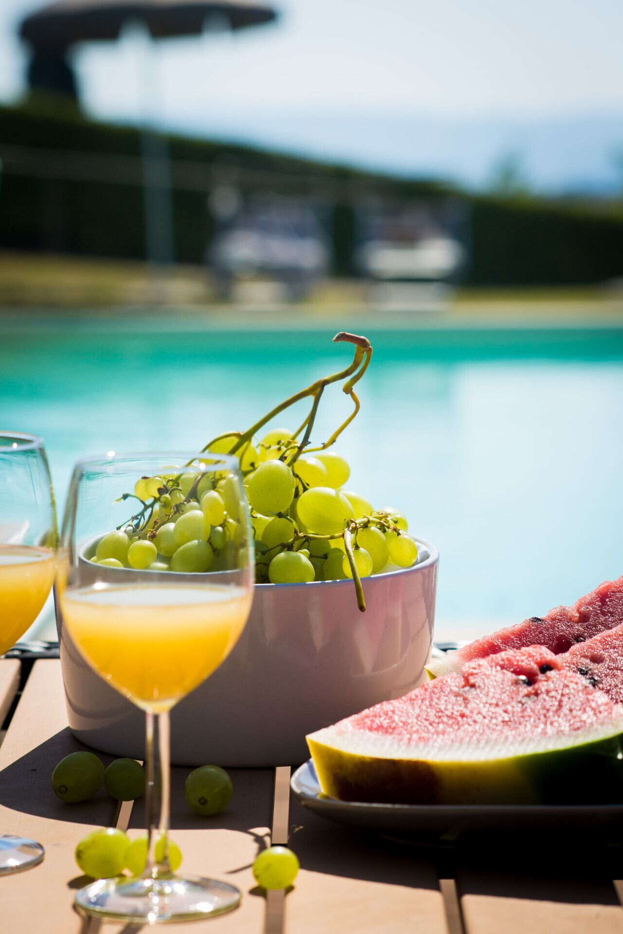 A table with a bowl of green grapes, a glass of orange juice, and a watermelon slice.