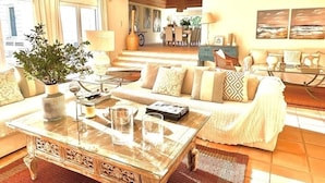 A living room with a sofa, coffee table, and a dining area in the background.